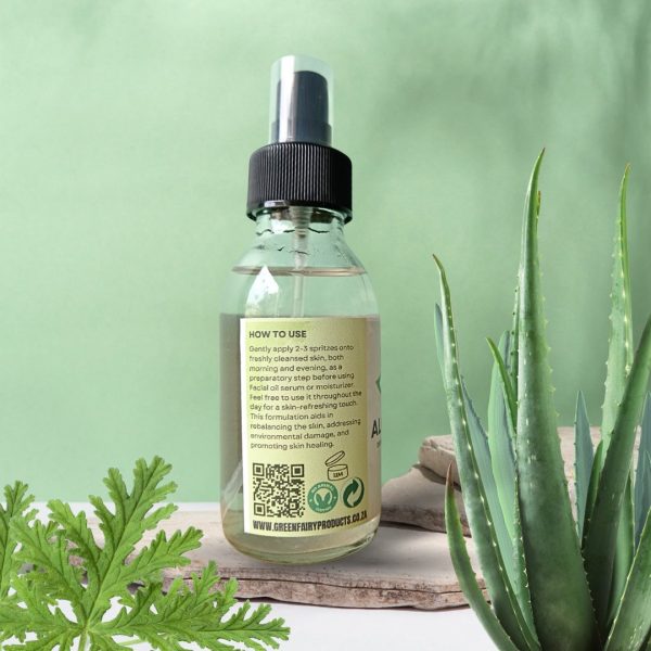 Green Fairy Products presents a refreshing Aloe Mist captured in a sleek glass bottle featuring a stylish black spray pump lid. The label showcases the how to use directions. Picture is decorated vibrant aloe and rose geranium leaves, embodying the natural essence within.